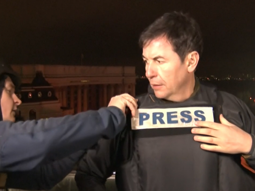 Gazetari detyrohet të vishet me jelekun anti-plumb pasi dëgjon bombardimet gjatë raportimit LIVE