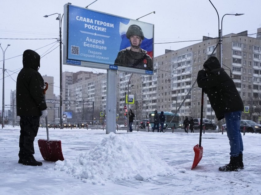 Punëtorët pastrojnë borën pranë portretit të ushtarit rus të shpërblyer për veprim në Ukrainë